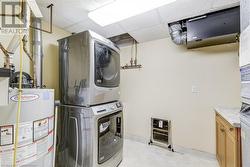 Washroom with cabinets, stacked washer / dryer, and water heater - 