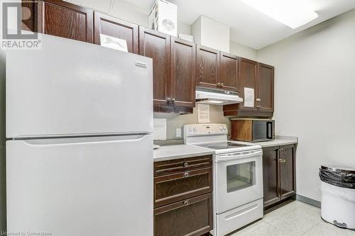 Kitchen featuring dark brown cabinetry and white appliances - 77 Governors Road Unit# 501, Dundas, ON - Indoor Photo Showing Kitchen