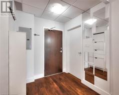 Corridor with dark hardwood / wood-style flooring, electric panel, and a paneled ceiling - 