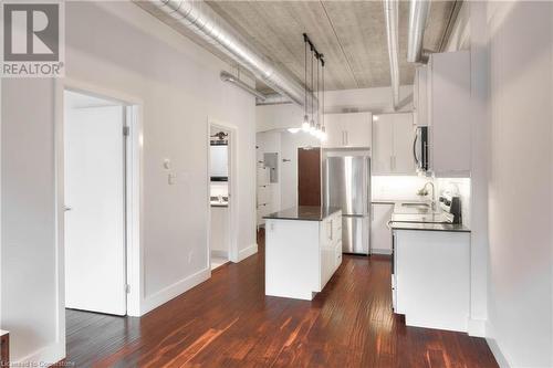 Kitchen featuring white cabinets, stainless steel appliances, hanging light fixtures, and dark wood-type flooring - 15 Devitt Avenue S Unit# 103, Waterloo, ON - Indoor Photo Showing Kitchen