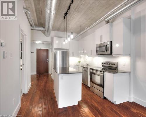 Kitchen featuring white cabinets, hanging light fixtures, appliances with stainless steel finishes, and dark wood-type flooring - 15 Devitt Avenue S Unit# 103, Waterloo, ON - Indoor Photo Showing Kitchen With Upgraded Kitchen