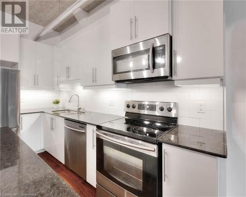 Kitchen with sink, stainless steel appliances, tasteful backsplash, dark hardwood / wood-style floors, and white cabinets - 15 Devitt Avenue S Unit# 103, Waterloo, ON - Indoor Photo Showing Kitchen With Upgraded Kitchen