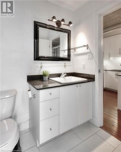 Bathroom with decorative backsplash, hardwood / wood-style floors, vanity, and toilet - 15 Devitt Avenue S Unit# 103, Waterloo, ON - Indoor Photo Showing Bathroom