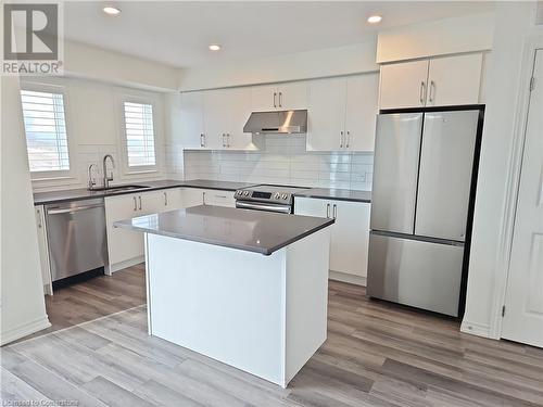 Kitchen featuring a center island, white cabinets, sink, light wood-type flooring, and appliances with stainless steel finishes - 235 Chapel Hill Dr Drive Unit# 16, Kitchener, ON - Indoor Photo Showing Kitchen