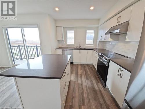 Kitchen featuring appliances with stainless steel finishes, backsplash, hardwood / wood-style flooring, white cabinets, and a kitchen island - 235 Chapel Hill Dr Drive Unit# 16, Kitchener, ON - Indoor Photo Showing Kitchen