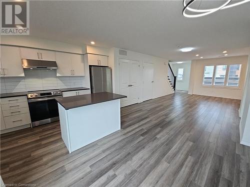 Kitchen featuring decorative backsplash, a center island, dark wood-type flooring, and appliances with stainless steel finishes - 235 Chapel Hill Dr Drive Unit# 16, Kitchener, ON - Indoor Photo Showing Kitchen