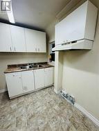 Kitchen featuring white cabinetry, sink, and exhaust hood - 