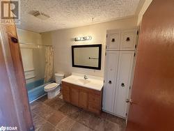 Full bathroom with vanity, toilet, shower / bathtub combination with curtain, and a textured ceiling - 