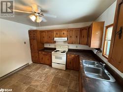 Kitchen featuring white range with electric cooktop, ceiling fan, sink, and a baseboard heating unit - 