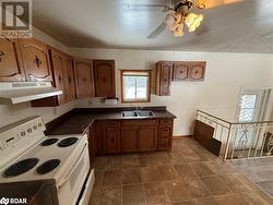 Kitchen featuring ceiling fan, sink, white electric stove, and exhaust hood - 