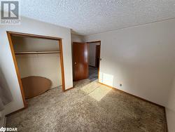 Unfurnished bedroom featuring a textured ceiling, carpet floors, and a closet - 