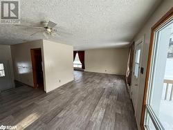 Empty room with a wealth of natural light, dark hardwood / wood-style flooring, ceiling fan, and a textured ceiling - 