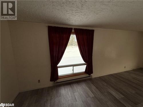 Empty room with dark hardwood / wood-style floors, a textured ceiling, and a baseboard radiator - 32299 Highway 17 E, Deep River, ON - Indoor Photo Showing Other Room