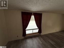 Empty room with dark hardwood / wood-style floors, a textured ceiling, and a baseboard radiator - 