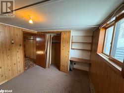 Unfurnished bedroom featuring carpet flooring, wood walls, and a closet - 