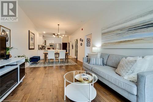 Living room featuring light wood-type flooring and a notable chandelier - 262 Dundas Street E Unit# 317, Hamilton, ON - Indoor Photo Showing Living Room With Fireplace