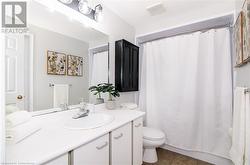 Bathroom featuring toilet, a shower with curtain, vanity, and tile patterned floors - 