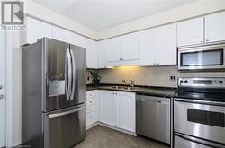 Kitchen featuring white cabinets, decorative backsplash, sink, and stainless steel appliances - 