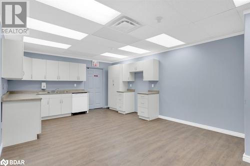 Kitchen with white dishwasher, light wood-type flooring, white cabinetry, and sink - 108 Russell Street N, Madoc, ON 