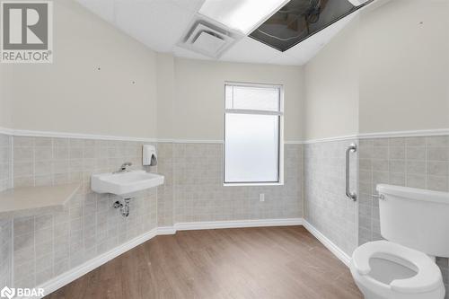 Bathroom featuring hardwood / wood-style floors, lofted ceiling, sink, toilet, and tile walls - 108 Russell Street N, Madoc, ON 