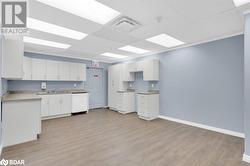 Kitchen with white cabinetry, dishwasher, light hardwood / wood-style floors, and sink - 