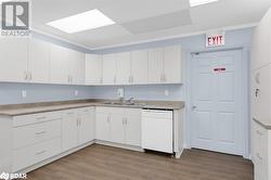 Kitchen featuring white cabinetry, sink, white dishwasher, and wood-type flooring - 