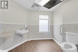 Bathroom with lofted ceiling, sink, toilet, tile walls, and wood-type flooring - 