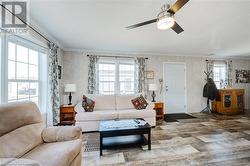 Living room featuring ceiling fan, crown molding, a healthy amount of sunlight, and wood-type flooring - 