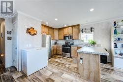 Kitchen featuring kitchen peninsula, ornamental molding, stainless steel appliances, sink, and light hardwood / wood-style flooring - 