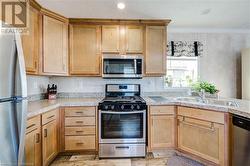 Kitchen with stainless steel appliances, light hardwood and crown molding, and sink - 