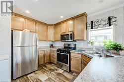 Kitchen with sink, light hardwood / wood-style flooring, ornamental molding, and appliances with stainless steel finishes - 