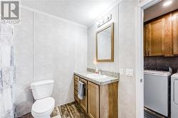 Bathroom featuring hardwood /crown molding, toilet, separate washer and dryer, and a textured ceiling - 