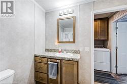 Bathroom with washer / clothes dryer, toilet, vanity, and ornamental molding - 