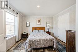 Bedroom featuring hardwood / wood-style flooring and ornamental molding - 