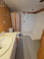 Bathroom with a shower, wood walls, concrete flooring, toilet, and vanity - 