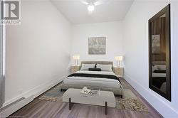 Bedroom with wood-type flooring, a baseboard radiator, and ceiling fan - 