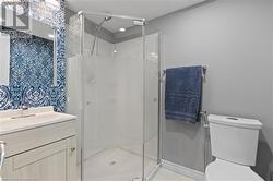 Bathroom featuring vanity, toilet, and a shower with door - 