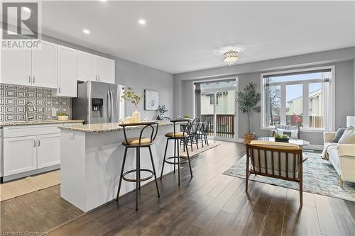 Kitchen featuring decorative backsplash, dark hardwood / wood-style flooring, a kitchen island, stainless steel fridge with ice dispenser, and white cabinetry - 1023 Devonshire Avenue Unit# 5, Woodstock, ON - Indoor