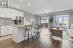 Kitchen featuring decorative backsplash, dark hardwood / wood-style flooring, a kitchen island, stainless steel fridge with ice dispenser, and white cabinetry - 