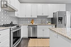 Kitchen with decorative backsplash, stainless steel appliances, white cabinetry, and sink - 