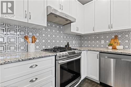 Kitchen with white cabinetry, light stone countertops, dark hardwood / wood-style floors, decorative backsplash, and appliances with stainless steel finishes - 1023 Devonshire Avenue Unit# 5, Woodstock, ON - Indoor Photo Showing Kitchen With Stainless Steel Kitchen With Upgraded Kitchen