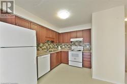 Kitchen with decorative backsplash, white appliances, and sink - 