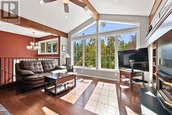 Living room has a vaulted ceiling with wood finished beams and is finished off with engineered auburn birch hardwood flooring - 