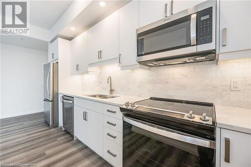 Kitchen with white cabinets, sink, dark hardwood / wood-style floors, decorative backsplash, and stainless steel appliances - 60 Charles Street Unit# 2205, Kitchener, ON - Indoor Photo Showing Kitchen With Stainless Steel Kitchen With Double Sink With Upgraded Kitchen