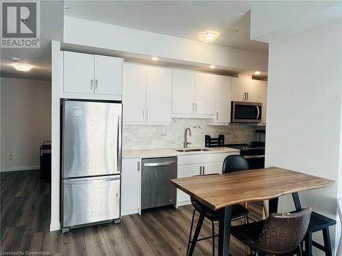 Kitchen with sink, white cabinets, dark wood-type flooring, and appliances with stainless steel finishes - 60 Charles Street Unit# 2205, Kitchener, ON - Indoor Photo Showing Kitchen With Stainless Steel Kitchen