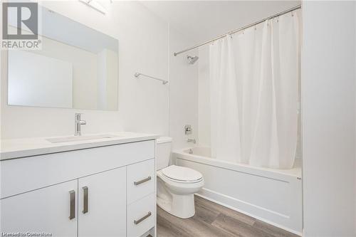 Full bathroom featuring toilet, hardwood / wood-style floors, vanity, and shower / tub combo with curtain - 60 Charles Street Unit# 2205, Kitchener, ON - Indoor Photo Showing Bathroom