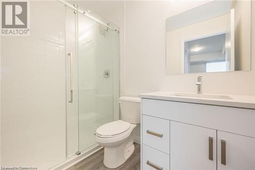 Bathroom featuring hardwood / wood-style floors, vanity, a shower with shower door, and toilet - 60 Charles Street Unit# 2205, Kitchener, ON - Indoor Photo Showing Bathroom