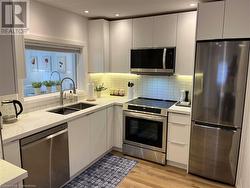 Kitchen with sink, white cabinets, stainless steel appliances, and light wood-type flooring - 