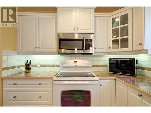 Electric range, built-in microwave & LED under cabinet lighting - 620 Arrowleaf Lane, Kelowna, BC - Indoor Photo Showing Kitchen