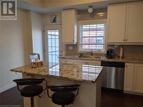 Kitchen with a breakfast bar, backsplash, sink, stainless steel dishwasher, and dark hardwood / wood-style floors - 9 Hyde Park Mews, Kitchener, ON - Indoor Photo Showing Kitchen